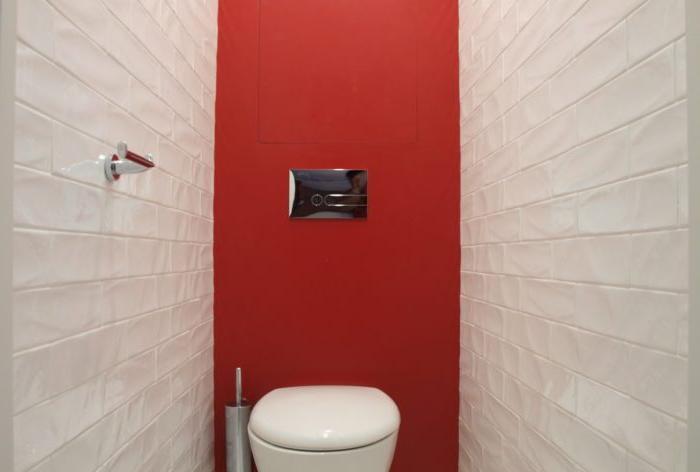 La combinazione di piastrelle e vernice rossa all'interno della toilette