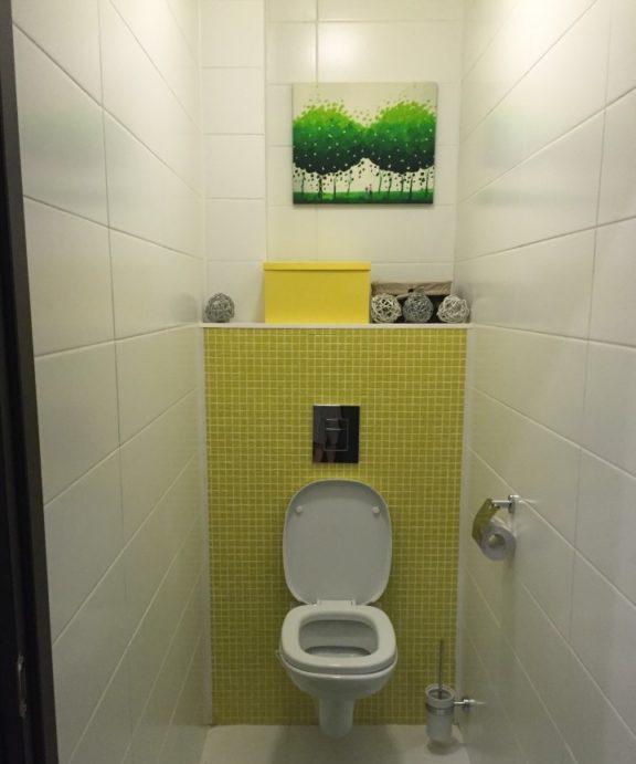 Servizi igienici in un appartamento con piastrelle bianche e mosaico giallo