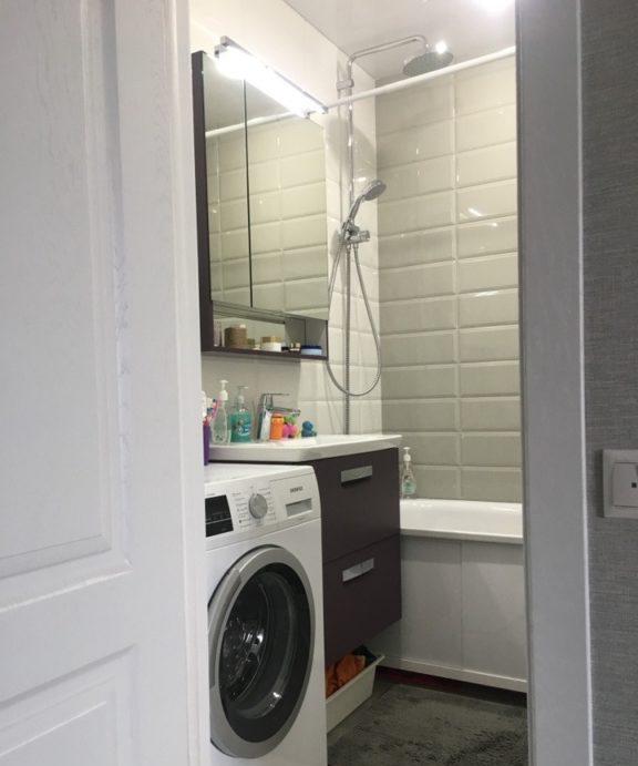 Piastrelle di mattoni bianchi lucidi nel bagno di Krusciov con lavatrice